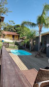 a wooden deck with a swimming pool and a house at Pousada Coração do Rosa - com Piscina Jacuzzi charme e conforto Pertinho do centrinho do Rosa in Praia do Rosa