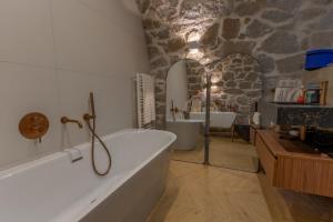 baño con bañera y pared de piedra en Le Miot - Duplex avec terrasse, en Ajaccio