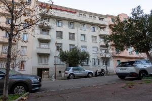 un gran edificio blanco con coches estacionados frente a él en Le Miot - Duplex avec terrasse, en Ajaccio