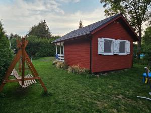 a small red house with white windows on a yard at Czerwone Domki Wartowo in Kołczewo