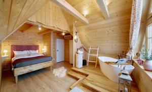 a log cabin bedroom with a large bed and a tub at Marusina Chalets in Szaflary