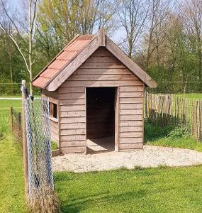 ein kleines Hundehaus auf einem Feld mit einem Zaun in der Unterkunft Camping de Peelweide in Grashoek