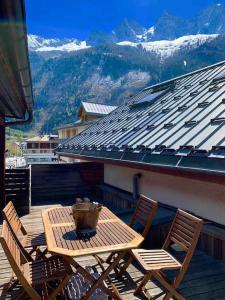 d'une table et de chaises en bois sur un balcon avec vue sur les montagnes. dans l'établissement 90m2 hypercentre, terrace, next to ski lift, à Chamonix-Mont-Blanc