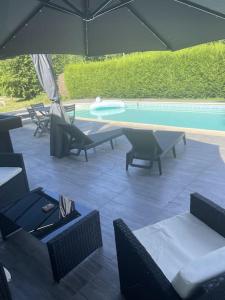 a patio with chairs and an umbrella and a pool at BY NEPTUNE - La Villa Courtenay Piscine Privée in Courtenay