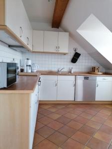 een keuken met witte kasten en een tegelvloer bij Ferienwohnung Fernblick in Osdorf