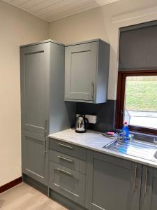 a kitchen with gray cabinets and a sink and a window at Welltrees Apartments 14 Dailly Road Maybole in Maybole