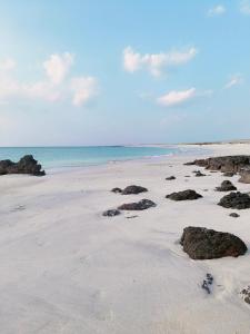 a beach with rocks in the sand and the ocean at Masirah Beach camp in Al Qārin