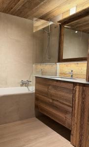 ein Badezimmer mit einem Waschbecken, einer Badewanne und einem Spiegel in der Unterkunft Paradis Perdu SKI IN & QUIET chalet 14 personnes in Les Collons