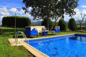 a swimming pool with a table and chairs next to a yard at Apartamentos Rurales Casa Ron in Coaña