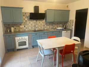 une cuisine avec des armoires bleues, une table et des chaises dans l'établissement Maison 4 CHAMBRES St Pierre du Perray, France, à Saint-Pierre-du-Perray