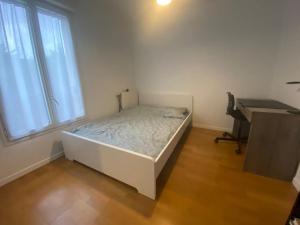 Cette chambre comprend un lit blanc, un bureau et une fenêtre. dans l'établissement Maison 4 CHAMBRES St Pierre du Perray, France, à Saint-Pierre-du-Perray