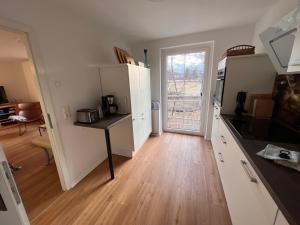 a kitchen with white cabinets and a wooden floor at Ferienhaus Bergblick - mit Sauna und Dampfbad und Yacuzzi in Sehma