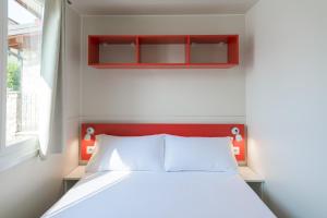 a bedroom with a white bed and a red headboard at Camping Fontanelle in Moniga