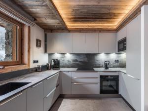 una cucina con mobili bianchi e soffitto in legno di Le Cheval Blanc et Le Loup Blanc, jacuzzi, hammam, skis aux pieds a Méribel Altre 9 foto