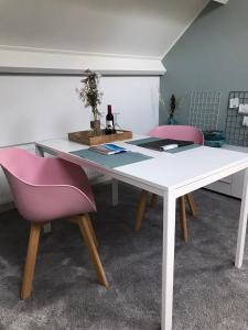 een witte tafel met twee roze stoelen in een kamer bij Hei-d-Away in Otterlo