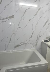 Baño blanco con bañera blanca y paredes de mármol en COZY ROOMS 25 min LIVERPOOL STREET, en Londres