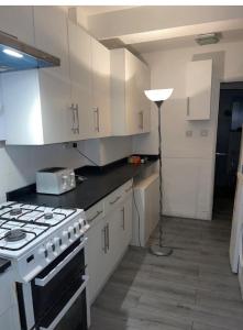 eine Küche mit einem Herd, weißen Schränken und einer Lampe in der Unterkunft COZY ROOMS 25 min LIVERPOOL STREET in London