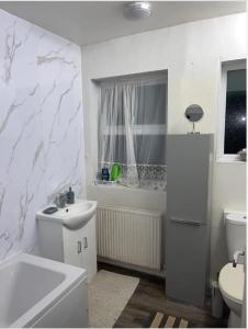 a white bathroom with a sink and a toilet at COZY ROOMS 25 min LIVERPOOL STREET in London