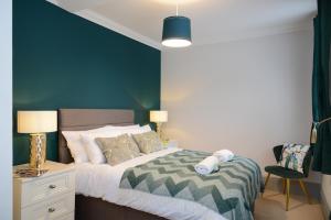 a bedroom with a bed with a green accent wall at The Old Brewery Boardroom - Winchester City Centre, Free Parking for 2 Cars, Sleeps 6 in Winchester