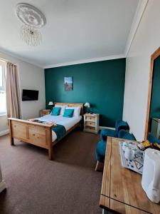 a bedroom with a bed and a couch and a table at Hildebrand Guest House in Tenby