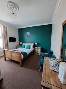 um quarto com uma cama, um sofá e uma mesa em Hildebrand Guest House em Tenby