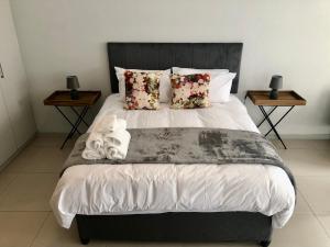 een slaapkamer met een groot bed en 2 tafels bij OAM The View Morningside in Johannesburg