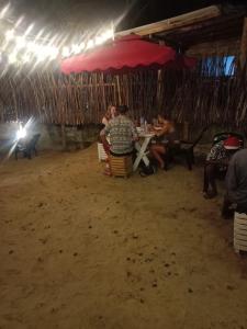 um grupo de pessoas sentadas numa mesa sob um guarda-chuva em Ocean Breeze Villa em Matara