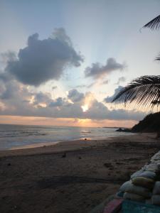a sunset on a beach with a palm tree at Ocean Breeze Villa in Matara