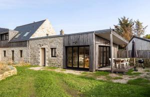 una vista exterior de una casa de piedra con puertas correderas de cristal en Maison pour 4 personnes proche de La Torche en Plomeur