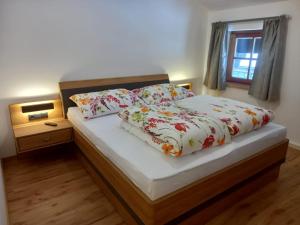 a bedroom with a bed with floral sheets and a window at Stefflgut Appartements in Maishofen