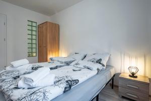 łóżko z białą i czarną pościelą i poduszkami w obiekcie Apartament Kawałek Podłogi w Piechowicach