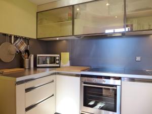 a kitchen with a stove and a microwave at Apartment Apartment Enzian N-720 by Interhome in Beatenberg