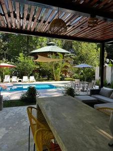 eine Terrasse mit einem Tisch, Stühlen und einem Pool in der Unterkunft La Amapola Lodge, Bungalow en Península de Osa. in Barrigones