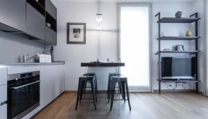 a kitchen with two bar stools and a tv at Italianway - Albani 20 in Milan