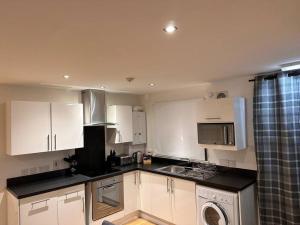een keuken met witte kasten en een wasmachine bij Apartment in Queens Court, Banchory in Inchmarlo