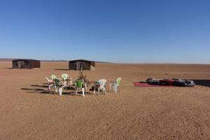a group of chairs in the middle of the desert at Sahara Berber Camp - Mhamid Discovery Camp in Mhamid el Rhozlane