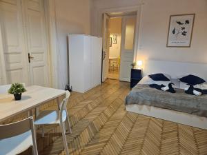 1 dormitorio con 1 cama, mesa y nevera en Chic Central Rooms, en Budapest