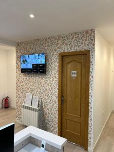 Habitación con puerta y TV en la pared en Hostal Flat55Madrid, en Madrid