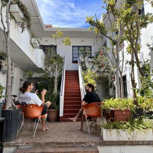 dos personas sentadas en sillas frente a una casa en Long Street Backpackers, en Ciudad del Cabo