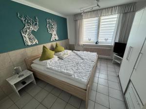 - une chambre avec un lit aux murs verts et des oreillers jaunes dans l'établissement 50107 Ferienhaus Cliner Sünn Whg. Borkum, à Carolinensiel