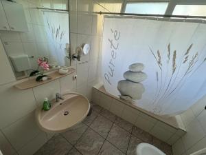 La salle de bains est pourvue d'un lavabo et d'un rideau de douche avec une pile de rochers. dans l'établissement 50107 Ferienhaus Cliner Sünn Whg. Borkum, à Carolinensiel