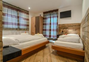 a bedroom with two beds and a tv on the wall at Abete rosso in Tesero