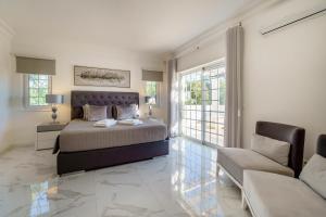 a bedroom with a king sized bed and a couch at Alcore Luxury Golf Villa at Alto Golf Alvor in Alvor