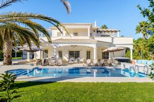 una grande casa bianca con piscina e palme di Alcore Luxury Golf Villa at Alto Golf Alvor ad Alvor