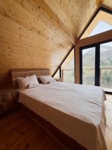 ein großes Bett in einem Zimmer mit einem großen Fenster in der Unterkunft Check Inn Merisi Spa and Resort in Gundauri