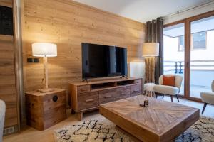 a living room with a flat screen tv on a wooden wall at Charming three-room apartment in Huez - Welkeys in LʼHuez
