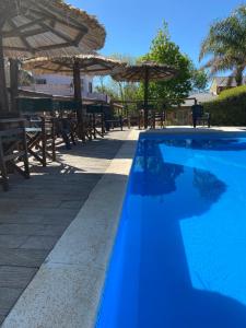a blue swimming pool with tables and umbrellas at Cabañas Peumayen in Colón