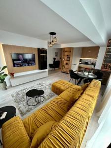 a living room with a yellow couch and a table at Balcescu Downtown Apartment in Bistriţa +21 photos