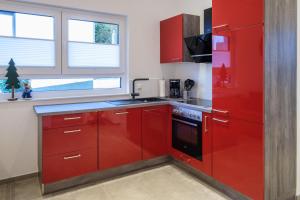 a red kitchen with red cabinets and a stove at Chalet Terraluna in Heimbach