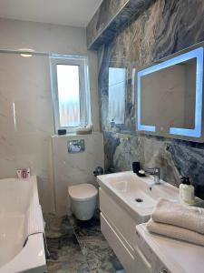a bathroom with a sink toilet and a tv on the wall at Balcescu Downtown Apartment in Bistriţa